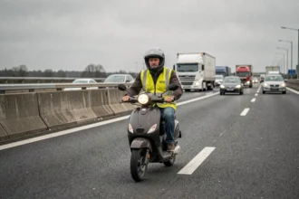 Scooter peu puissant sur une autoroute française entouré de poids lourds, illustrant le danger pour les deux-roues de faible cylindrée
